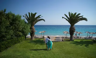 a person walking on the grass near the beach at The Ixian Grand & All Suites - Adults Only Hotel in Ixia