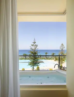 a view from a window of a bath tub with the ocean at The Ixian Grand & All Suites - Adults Only Hotel in Ixia