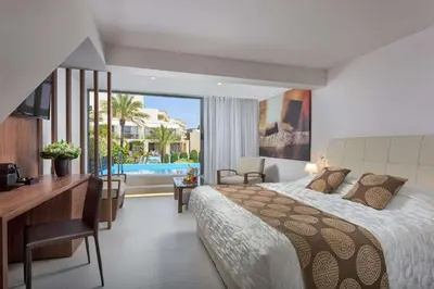 a bedroom with a bed and a desk and a pool at The Ixian Grand & All Suites - Adults Only Hotel in Ixia