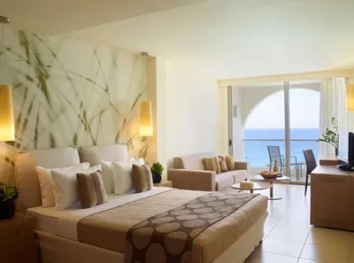 a bedroom with a large bed and a living room at The Ixian Grand & All Suites - Adults Only Hotel in Ixia