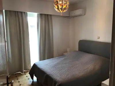 a bedroom with a bed and a chandelier and a window at Jacob Apartments in Center of Rhodes in Rhodes Town