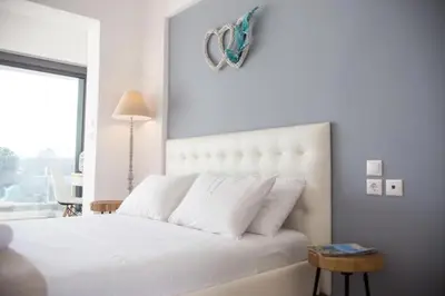 a white bedroom with a large white bed and a window at Nitsa Studio in Faliraki