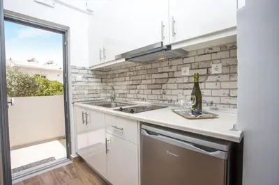 a kitchen with white cabinets and a sink and a window at Nitsa Studio in Faliraki