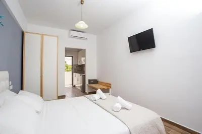 a bedroom with a white bed and a tv at Nitsa Studio in Faliraki