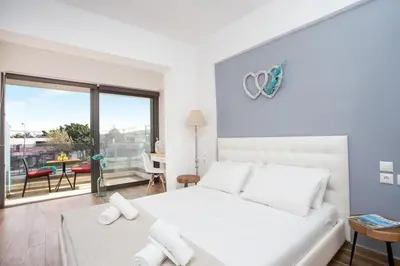 a white bedroom with a large bed and a balcony at Nitsa Studio in Faliraki