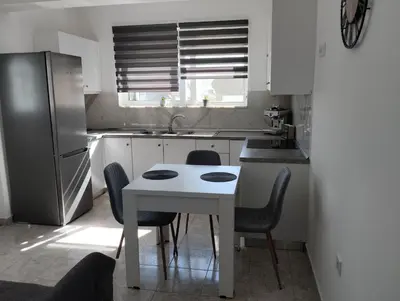 a kitchen with a white table and chairs and a refrigerator at Palma Apartment in Faliraki