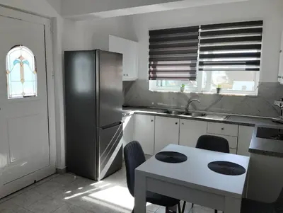 a kitchen with a stainless steel refrigerator and a table at Palma Apartment in Faliraki