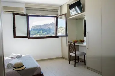 a room with a bed and a desk and a window at Helen Superior Suite in Líndos
