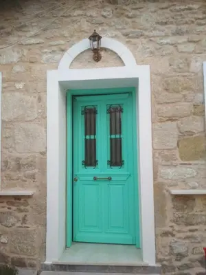 a green door on a stone wall with a light above it at Rhodes Heaven Rose in Malona Village