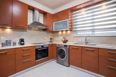 a kitchen with wooden cabinets and a washing machine at Christina's House in Afantou