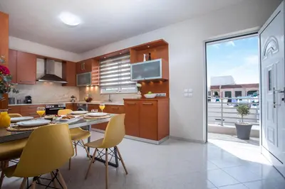 a kitchen with a table and yellow chairs in it at Christina's House in Afantou