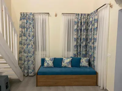 a room with a blue couch in front of windows at Aleminas Rooms 1 in Symi