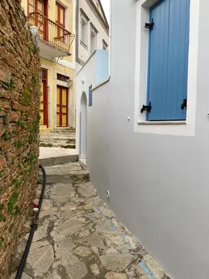 an alley with a blue door on a white building at Aleminas Rooms 1 in Symi