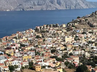 a town on a hill next to the water at Aleminas Rooms 1 in Symi