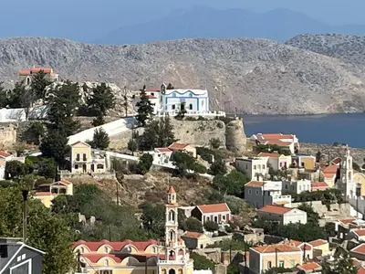 a town on a hill with houses and a body of water at Aleminas Rooms 1 in Symi