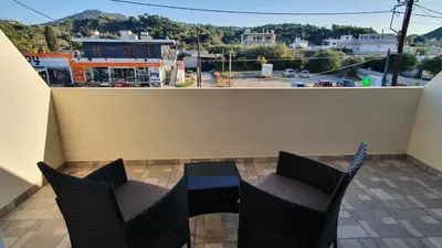 a balcony with chairs and a table and a view of a city at Ma Maison Bleue in Kremasti