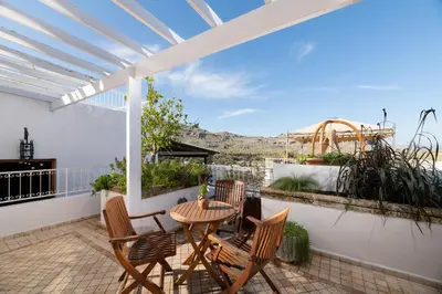 a patio with a table and chairs on a balcony at Villa Venetoklis in Líndos