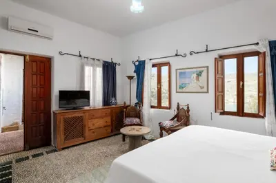 a bedroom with a bed and a tv and a table at Villa Venetoklis in Líndos