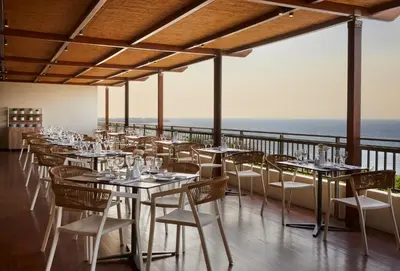 a restaurant with tables and chairs with the ocean in the background at Amus Hotel & Spa in Ixia