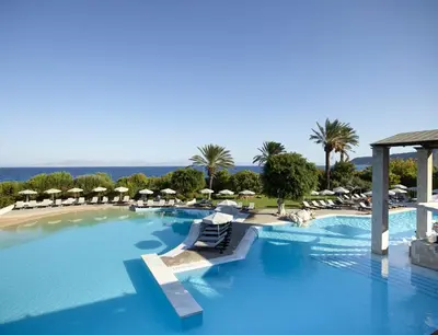 a large swimming pool with lounge chairs and umbrellas at Amus Hotel & Spa in Ixia