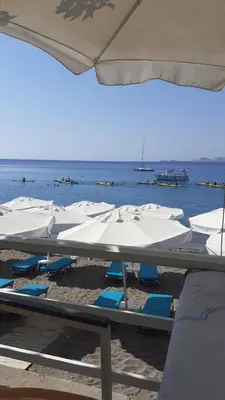 a group of white umbrellas and chairs on a beach at Artoria Apartment 2 First Floor in Haraki