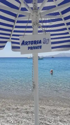 a sign on the beach under an umbrella at Artoria Apartment 2 First Floor in Haraki
