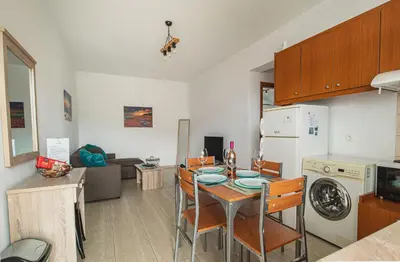 a kitchen and living room with a table and chairs at Basiliki's Apartments in Archangelos