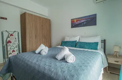 a bedroom with a blue bed with towels on it at Basiliki's Apartments in Archangelos