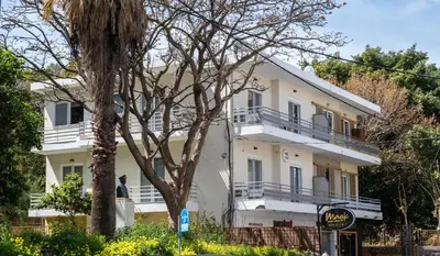 a white building with a tree in front of it at Mini City Escape in Rhodes Town