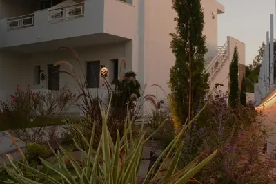 a person standing outside of a building with plants at Anemone Premium Suites Faliraki in Faliraki