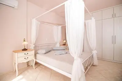 a white bedroom with a canopy bed with curtains at Villa Regina - Luxury and Comfort in Lachania
