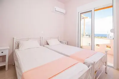 a white bedroom with two beds and a large window at Villa Regina - Luxury and Comfort in Lachania