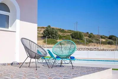 two chairs sitting on a patio next to a pool at Regina Villa - Family Dream with double pool in Lachania