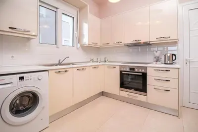 a white kitchen with a washer and a dishwasher at Regina Villa - Family Dream with double pool in Lachania