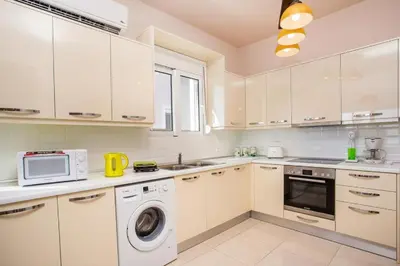 a kitchen with white cabinets and a washer and dryer at Regina Villa - Family Dream with double pool in Lachania