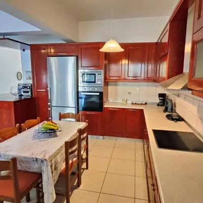 a kitchen with wooden cabinets and a table with chairs at Evaggelia's Private House in Fanes Rhodes in Phanaes