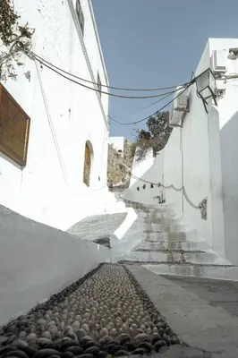 an alley with white buildings and cobblestone streets at Kilistra Lindian Living in Líndos