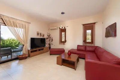 a living room with a red couch and a flat screen tv at Vlasis' Eden Villa - Islander's Home Collection in Sálakos