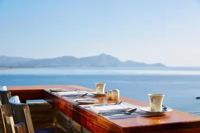 a wooden table with plates and utensils on top of the water at Lindos Blu Luxury Hotel-Adults only in Líndos