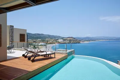 a swimming pool with a table and a view of the water at Lindos Blu Luxury Hotel-Adults only in Líndos