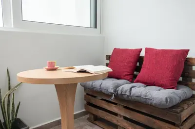 a couch with red pillows and a table with a book at Naelia in Pastida