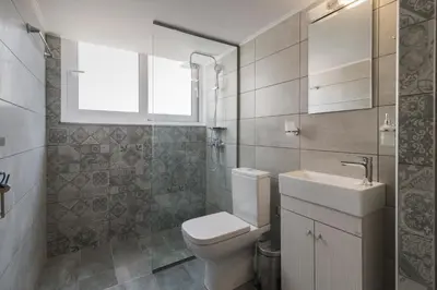 a bathroom with a toilet and a sink and a window at Mailo&Luke apartments in Rhodes Town