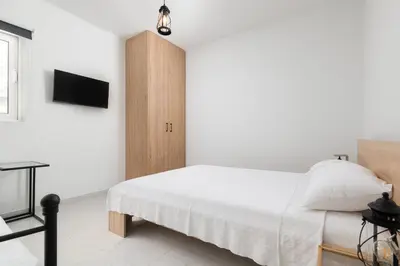 a white bedroom with a bed and a cabinet at Mailo&Luke apartments in Rhodes Town