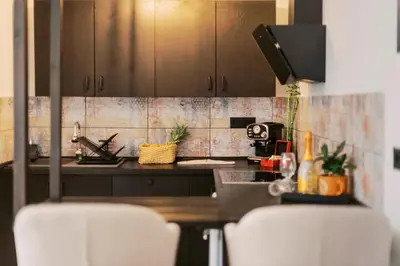 a kitchen with brown cabinets and two white chairs at Mailo&Luke apartments in Rhodes Town
