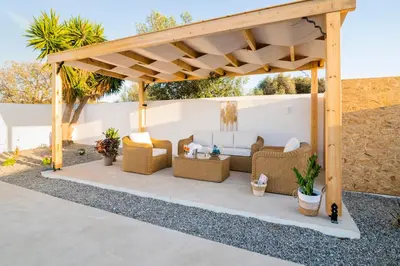 a pergola with couches and chairs under it at Villa Eleni in Soroni