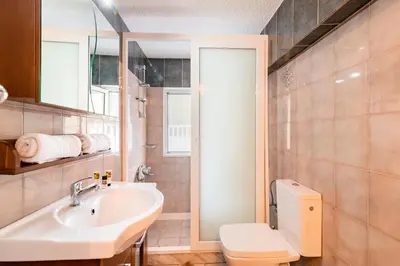 a bathroom with a sink and a toilet and a mirror at Villa Eleni in Soroni