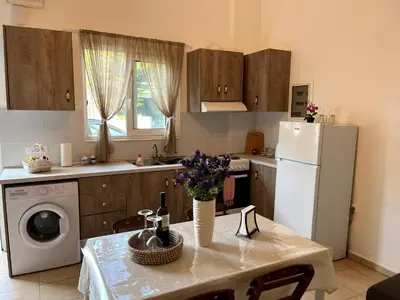 a kitchen with a table and a white refrigerator at Irene’s house in Koskinou