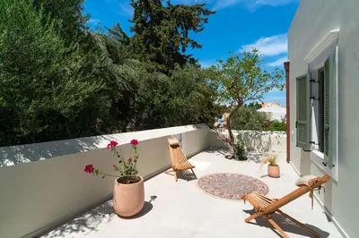 a patio with chairs and flowers on a wall at Nisomar Suites in Symi