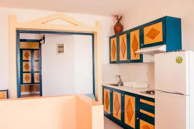a kitchen with a white refrigerator and colorful cabinets at Limanaki Seafront Apartments in Faliraki