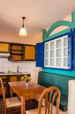 a kitchen with a wooden table and blue cabinets at Limanaki Seafront Apartments in Faliraki